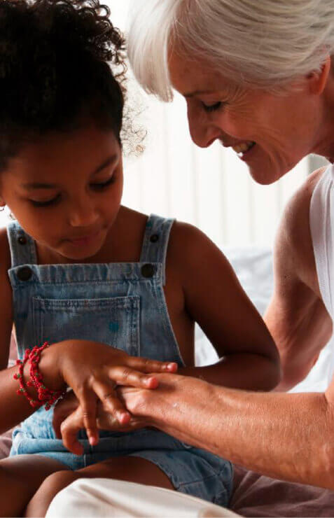 Old lady holding a little mixed race girl on her lap, stroking her hand